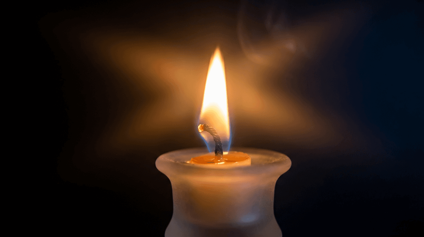 Glowing candle flame in darkness with volumetric light rays, warm glow, symbolic spiritual lighting.